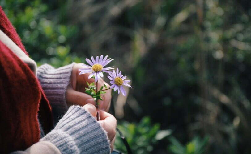 Girl holding flowers thinking while feeling grief over her bereavement